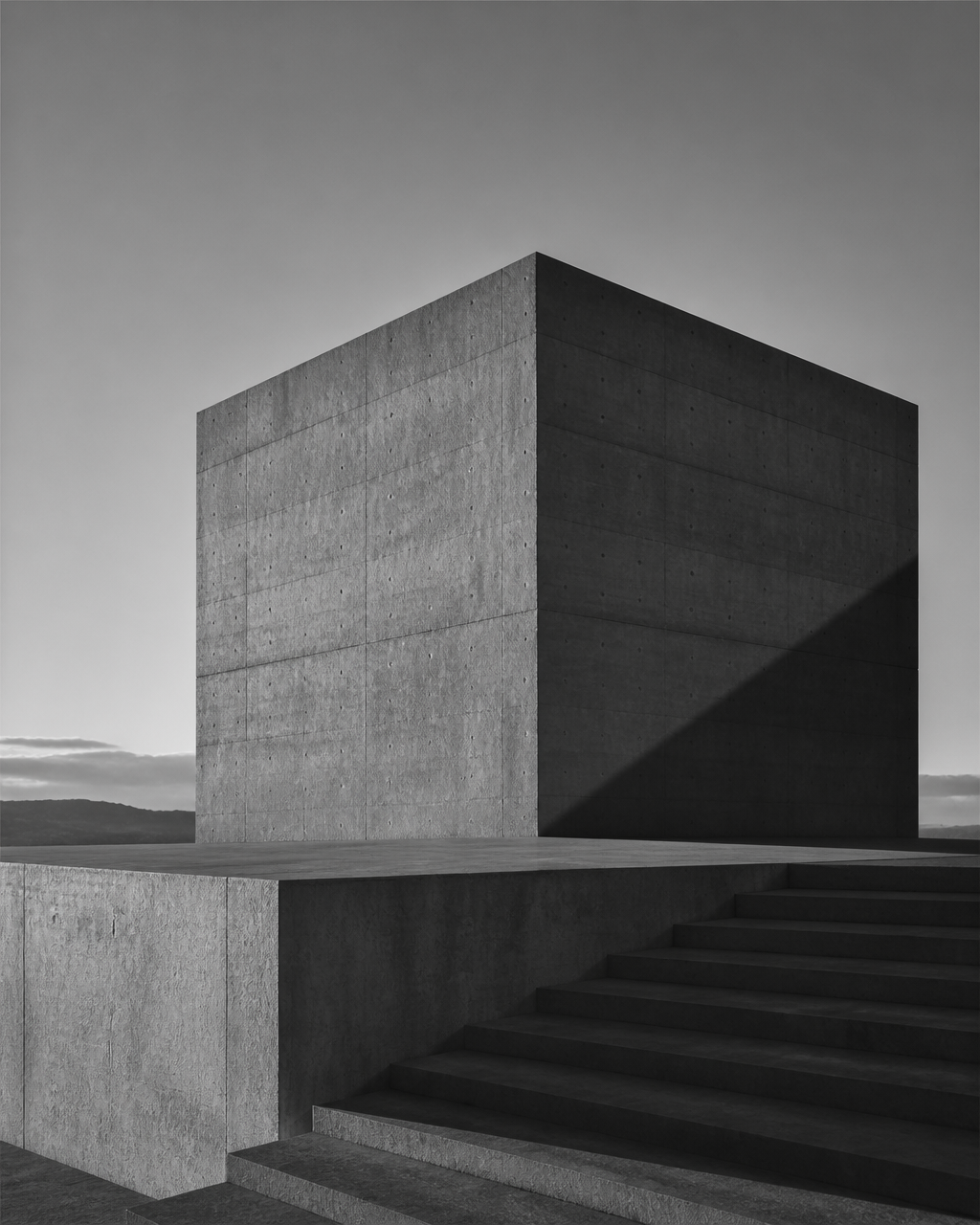 Minimalist brutalist concrete monolith against a pale dawn sky